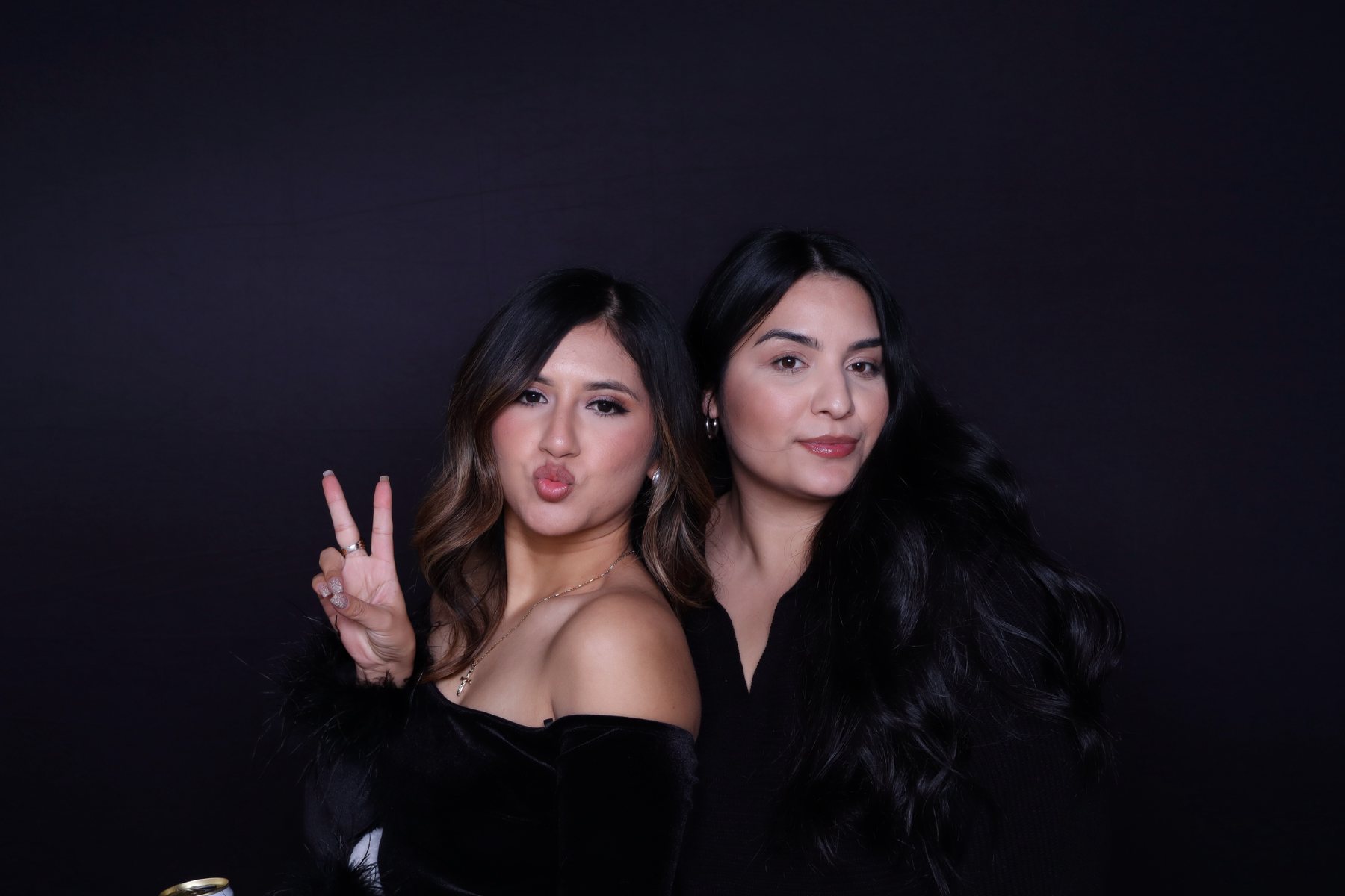 Two guests posing together against a dark photo booth backdrop
