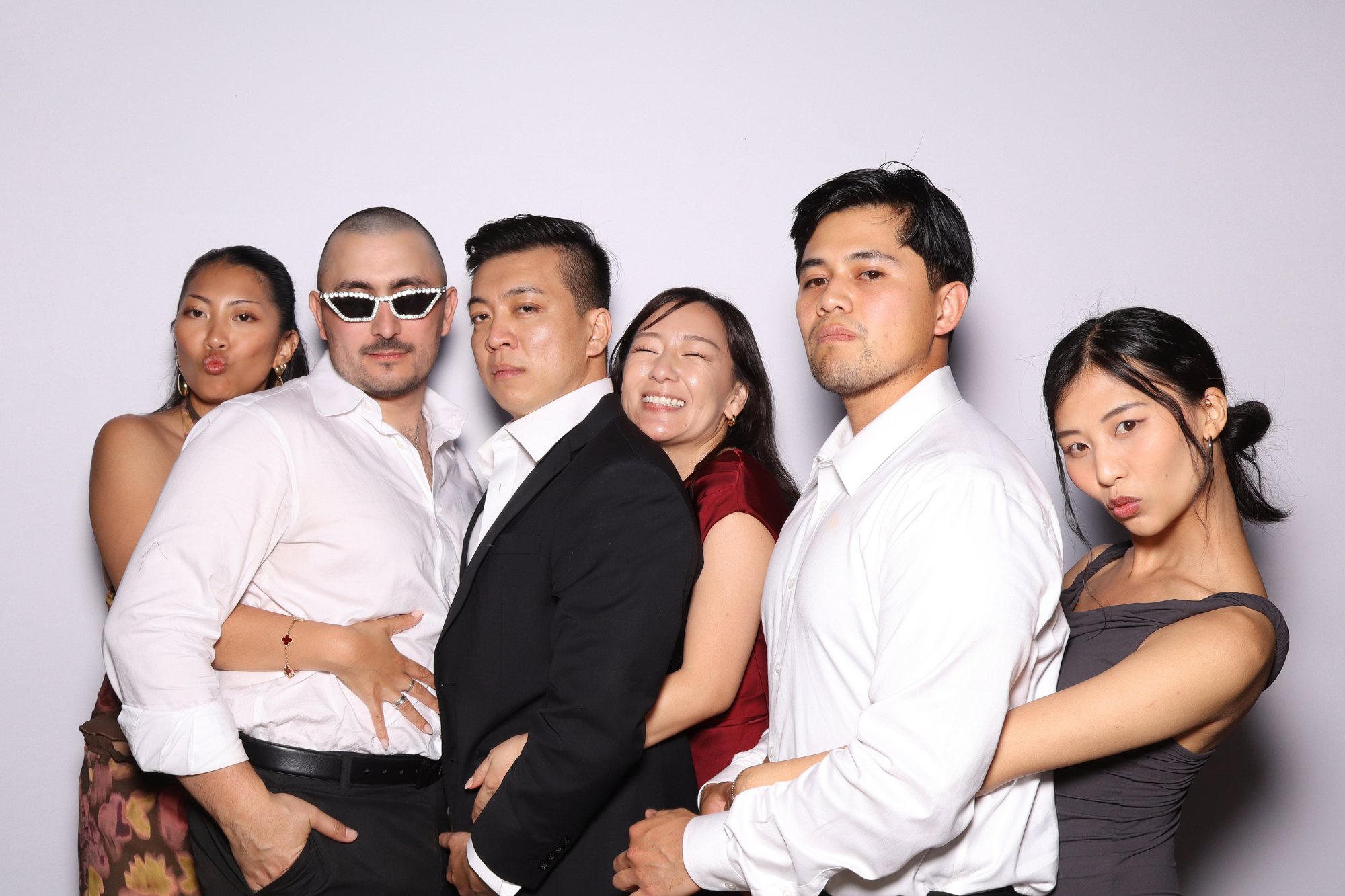 Six guests posing together against a light photo booth backdrop
