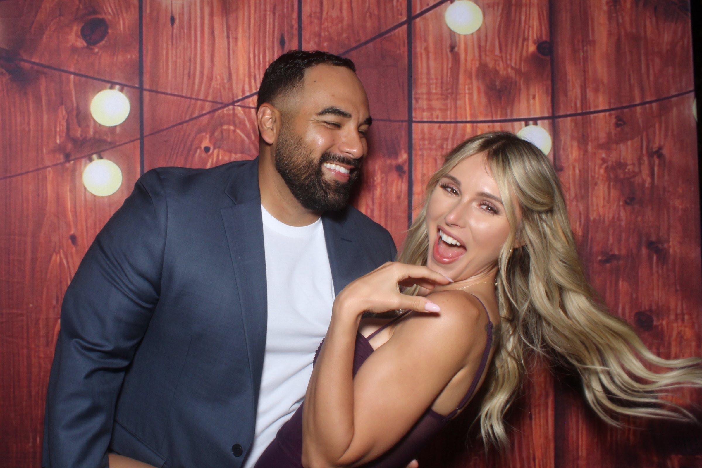 Wedding couple smiling together in front of a rustic photo booth backdrop